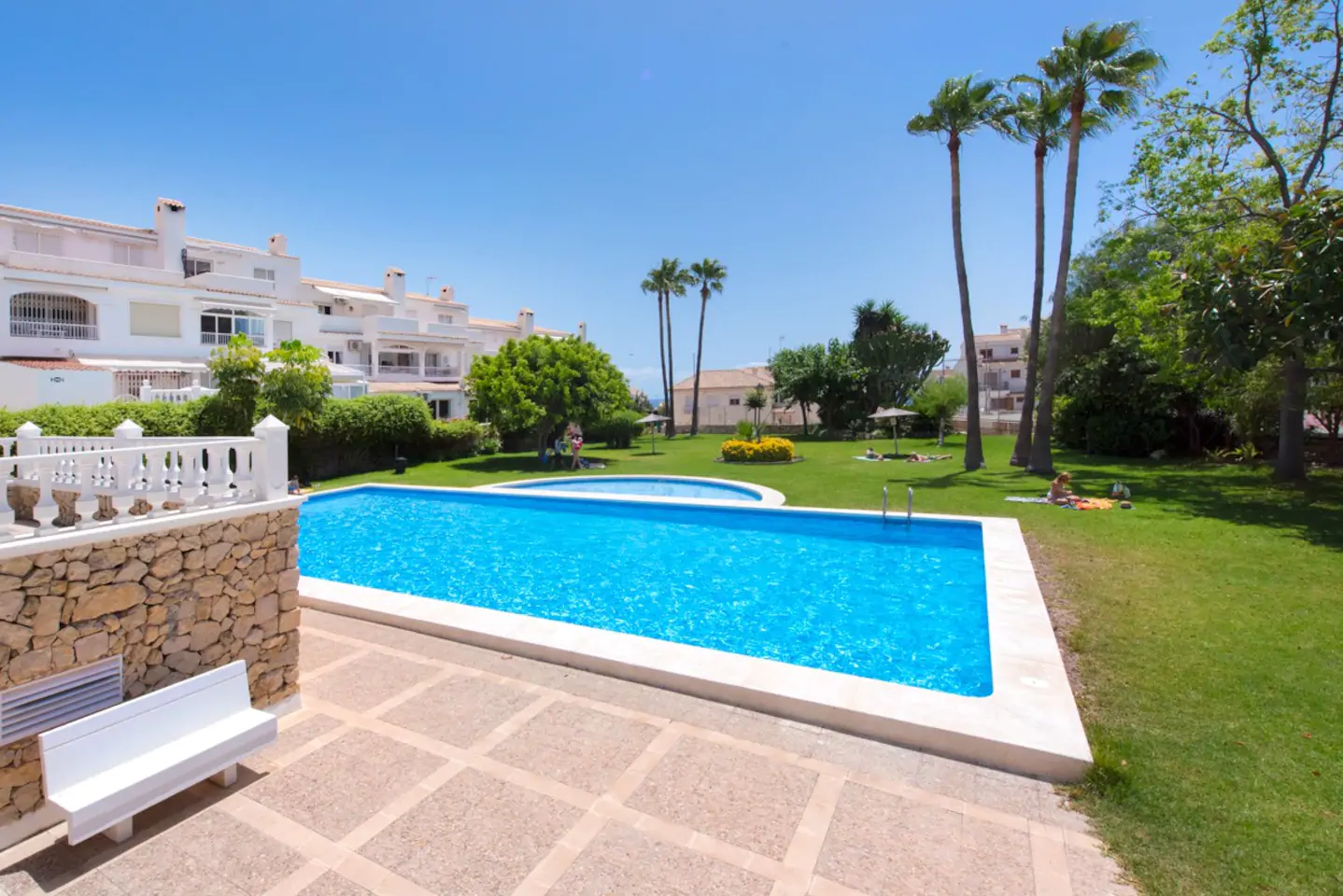 Piscina turquesa con palmeras y jardines